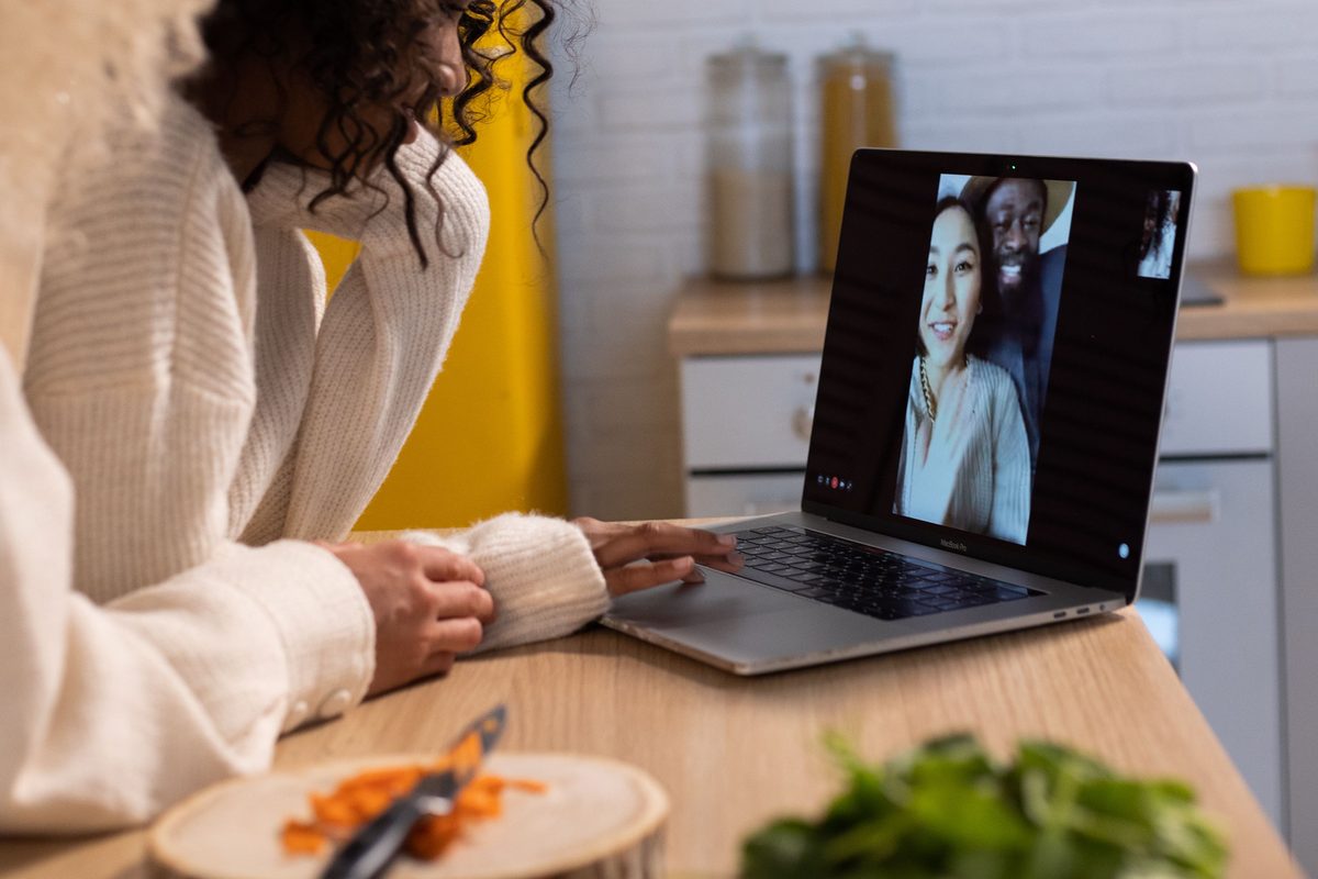 Forælder ved køkkenbordet i en videosamtale på den bærbare computer