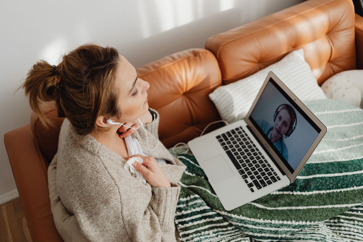 Kvinde i sofaen med høretelefoner og bærbar computer til en samtale over video