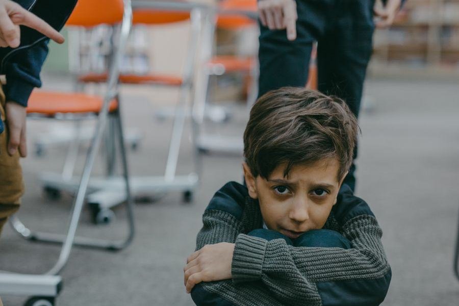 Trist dreng sidder på gulvet i et klasselokale, når skolen bliver svær